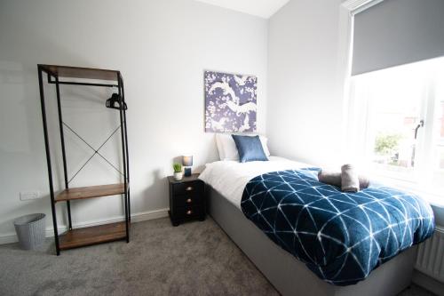 um quarto com uma cama com um cobertor azul e uma janela em Ideal Lodgings in Royton em Royton