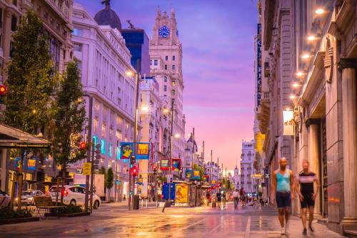 a city street at night with people walking down the street at Woohoo Rooms Fuencarral in Madrid