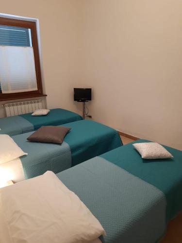 three blue beds in a room with a window at Appartamento L'Acero in Cupello