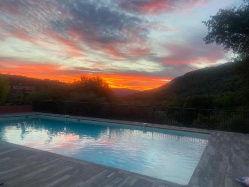 a swimming pool with a sunset in the background at Les Mazets de la Cascade in Salernes