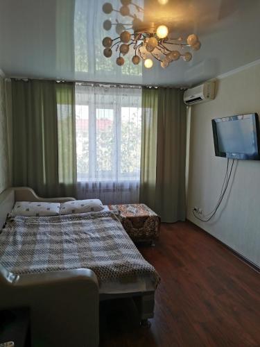 Schlafzimmer mit einem Bett und einem Flachbild-TV in der Unterkunft 1 комн квартира в центре in Qostanai