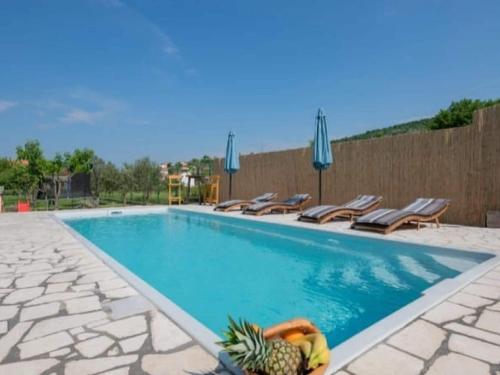 a swimming pool with chairs and a pineapple next to it at Adorable holiday home with swimming pool in Imotski