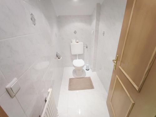 a white bathroom with a toilet and a door at Pretty Holiday Home in Mayerhofen with Balcony in Mayrhofen