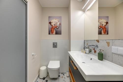 a bathroom with a sink and a toilet and a mirror at Downtown Apartments City Center Aura 40 in Gdańsk