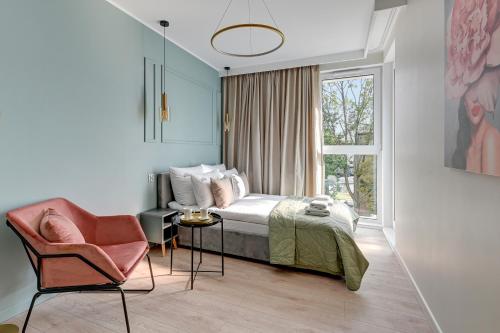 a bedroom with a bed and a chair and a window at Downtown Apartments City Center Aura 40 in Gdańsk