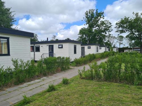 a row of white mobile homes in a yard at Holiday Chalet Basic in Hensbroek