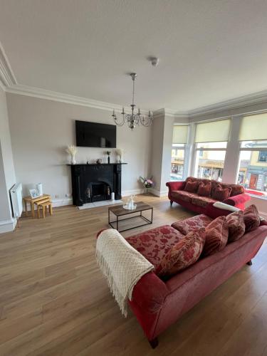 a living room with a red couch and a fireplace at 57 Main Street Newcastle Luxury Central Apartment in Newcastle