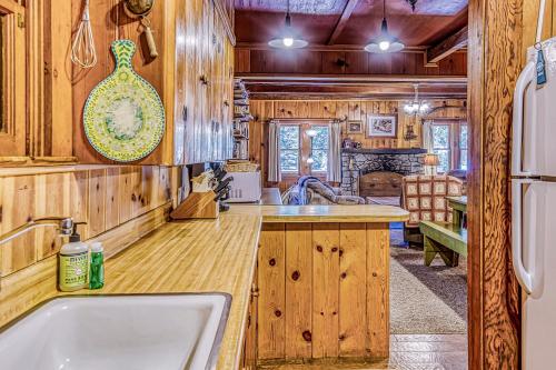 uma cozinha com armários de madeira, um lavatório e um frigorífico em Alpine Cottage em Shaver Lake