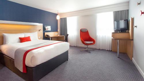 Habitación de hotel con cama y silla roja en Holiday Inn Express London Limehouse, an IHG Hotel, en Londres
