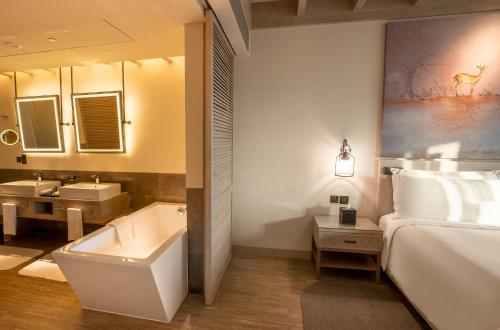a bathroom with a bed and a tub and a sink at Saadiyat Rotana Resort and Villas in Abu Dhabi