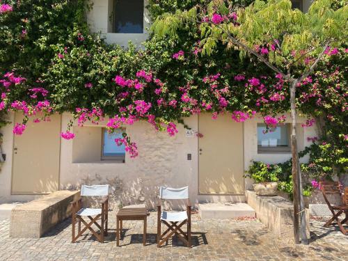 a group of chairs under a tree with pink flowers at Nova Casa com Piscina no Convento das Bernardas in Tavira