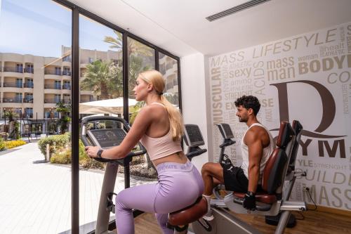 a man and a woman exercising on exercise bikes in a gym at Domina Zagarella Sicily in Santa Flavia