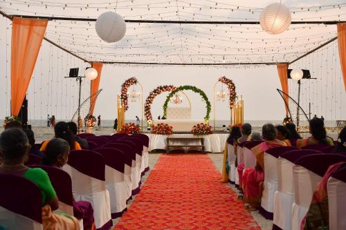 un groupe de personnes assis dans une salle de banquet avec un tapis rouge dans l'établissement Alleppey Palm Beach Resort & Cafe, à Alappuzha