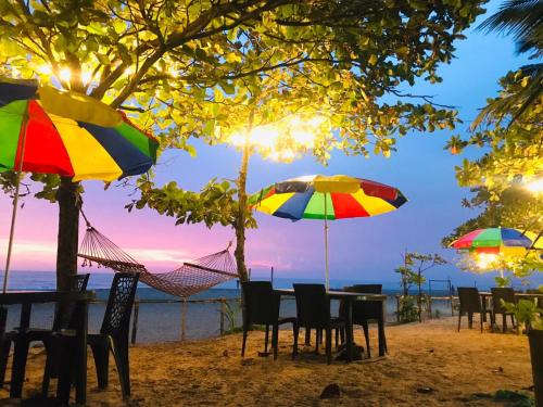 - une table et des chaises avec des parasols sur une plage dans l'établissement Alleppey Palm Beach Resort & Cafe, à Alappuzha