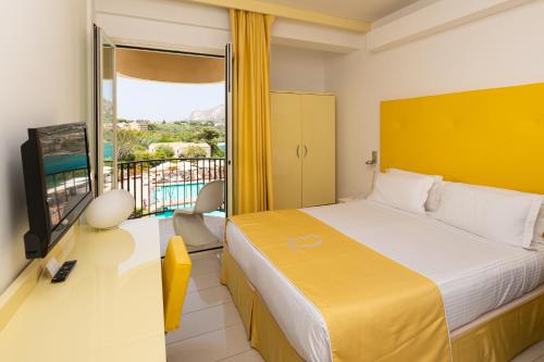 a bedroom with a bed and a tv and a balcony at Domina Zagarella Sicily in Santa Flavia
