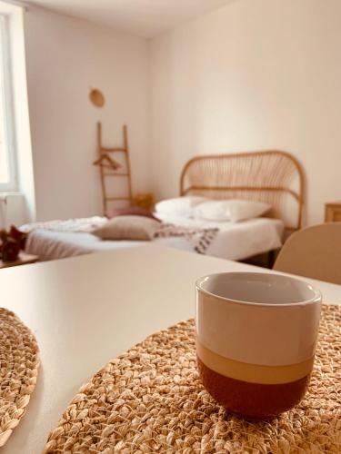 a coffee cup sitting on a table with two beds at Studio Renard, style bohème et atypique, Curistes in Luxeuil-les-Bains