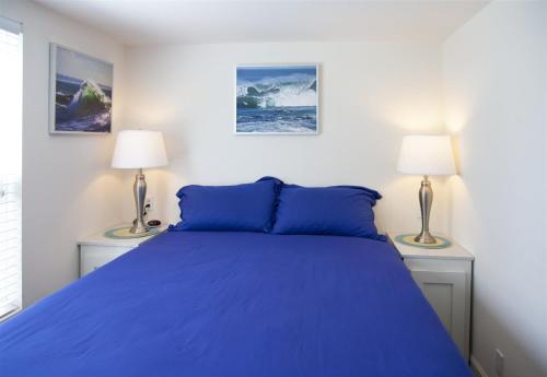 een slaapkamer met een bed met blauwe lakens en 2 lampen bij H - Cochito in Fort Bragg
