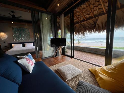 a bedroom with a bed and a television and the beach at Sealord Naithon Beachfront Villa in Nai Thon Beach
