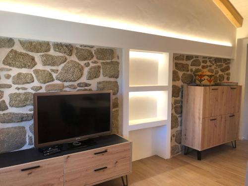 a living room with a tv on a stone wall at STAZZU LU CHISSONI in Luogosanto