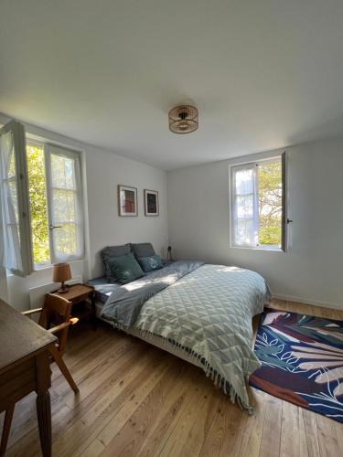 une chambre avec un lit et deux fenêtres dans l'établissement La Maison du Gardien, à La Rochelle