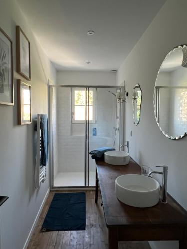 La salle de bains est pourvue d'un lavabo, d'un miroir et d'une douche. dans l'établissement La Maison du Gardien, à La Rochelle
