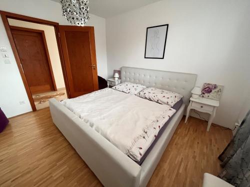 a white bed in a bedroom with a wooden floor at Apartmán Mikulov in Mikulov