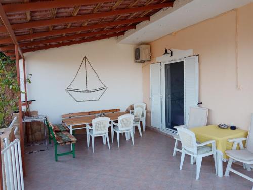 een patio met witte stoelen en een tafel en een zeil aan de muur bij Triopetra hill view in Triopetra