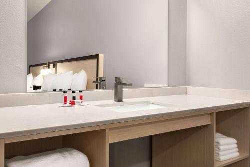ein Bad mit einem Waschbecken und einem Spiegel in der Unterkunft Ramada by Wyndham Marina in Marina