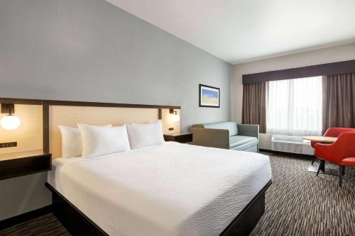 a hotel room with a large bed and a chair at Ramada by Wyndham Marina in Marina