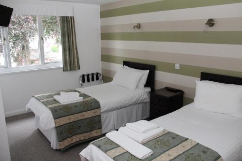 two beds in a room with striped walls at Ravenswood Social Club in Banchory