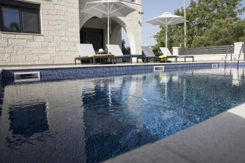 a swimming pool with chairs and umbrellas next to a house at Villa-Azalea in Almirida