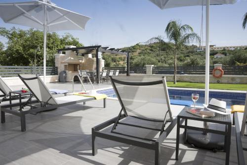 two chairs and a table and an umbrella on a patio at Villa-Azalea in Almirida