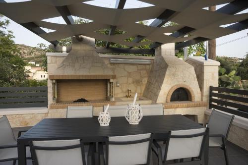 a patio with a black table and chairs and an outdoor oven at Villa-Azalea in Almirida