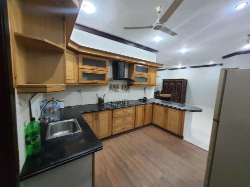 cocina con armarios de madera, fregadero y nevera en Patel Residency Apartment en Karachi