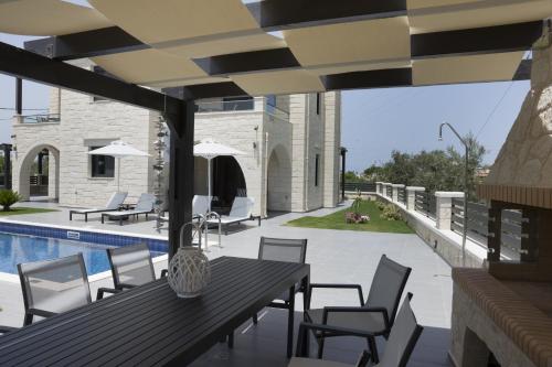 a patio with a table and chairs and a pool at Villa-Azalea in Almirida
