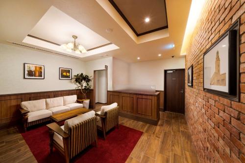 a waiting room with a couch and chairs and a brick wall at Best Western Hotel Fino Shin-Yokohama in Yokohama