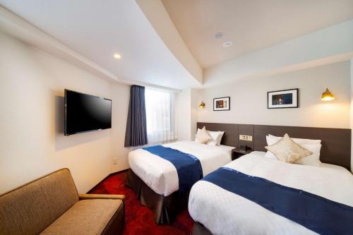 a hotel room with two beds and a couch at Best Western Hotel Fino Shin-Yokohama in Yokohama