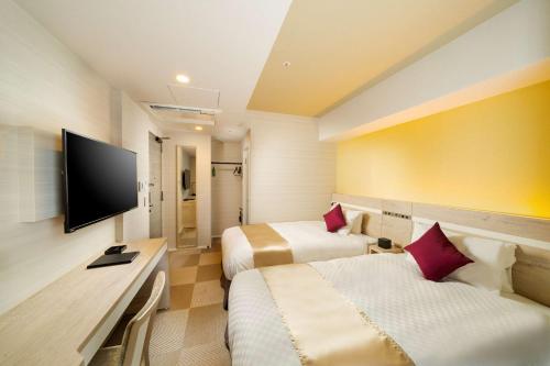 a hotel room with two beds and a flat screen tv at Best Western Hotel Fino Tokyo Akasaka in Tokyo