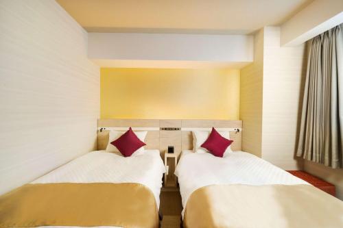 two beds in a hotel room with red pillows at Best Western Hotel Fino Tokyo Akasaka in Tokyo