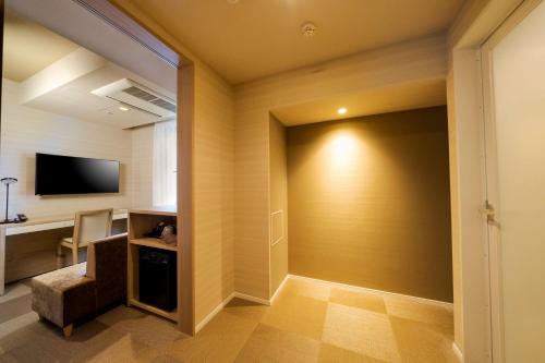 a room with a wall with a television and a chair at Best Western Hotel Fino Tokyo Akasaka in Tokyo
