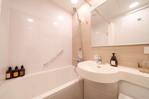 a bathroom with a sink and a tub and a mirror at Best Western Hotel Fino Tokyo Akasaka in Tokyo