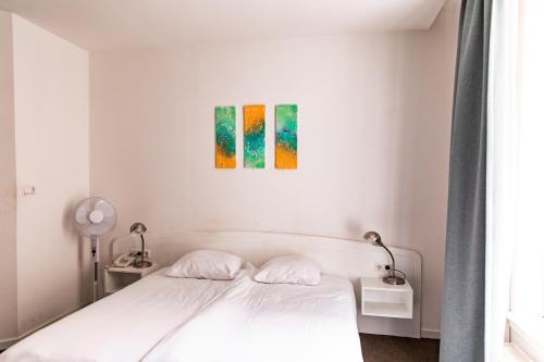 a bedroom with a white bed and a painting on the wall at Ambassador City Centre Hotel in Haarlem