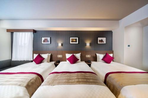 two beds in a hotel room with pink pillows at Best Western Plus Fukuoka Tenjin-minami in Fukuoka