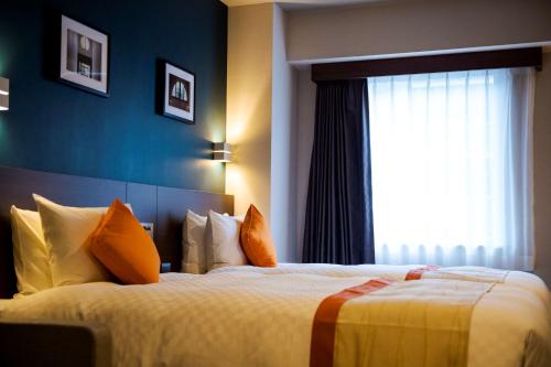 a hotel room with two beds and a window at Best Western Plus Fukuoka Tenjin-minami in Fukuoka