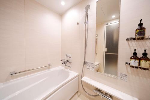 a bathroom with a tub and a sink and a mirror at Best Western Plus Fukuoka Tenjin-minami in Fukuoka