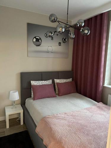 a bedroom with a bed with red curtains and a chandelier at Apartament Alan in Ustrzyki Dolne