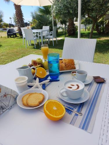 a table with a breakfast of coffee and orange juice at B&B Il Gabbiano in Cittadella del Capo