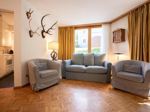 uma sala de estar com duas cadeiras e um sofá em Apartment Chesa Cresta by Interhome em Surlej