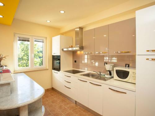 a kitchen with white cabinets and a sink and a microwave at Apartment Olivia by Interhome in Pićan