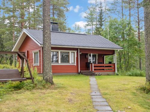 uma cabana vermelha na floresta com um alpendre em Holiday Home Lepokunnas by Interhome em Suomussalmi